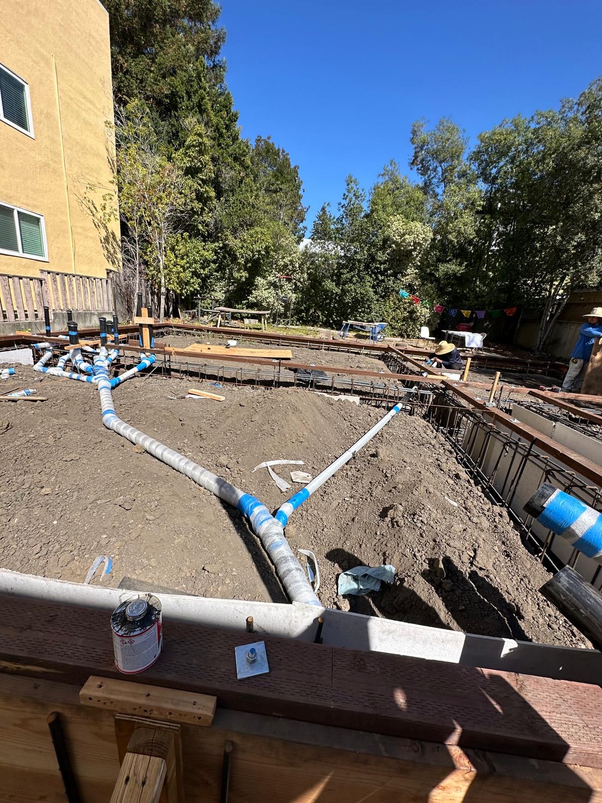 Rough plumbing laid out across a foundation before the slab pour