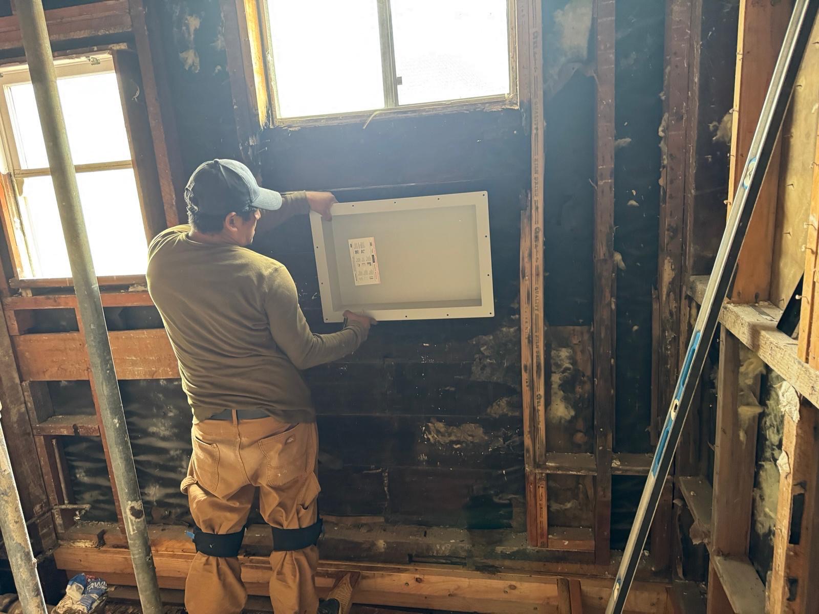 Technician setting a shower niche in the framed bathroom wall