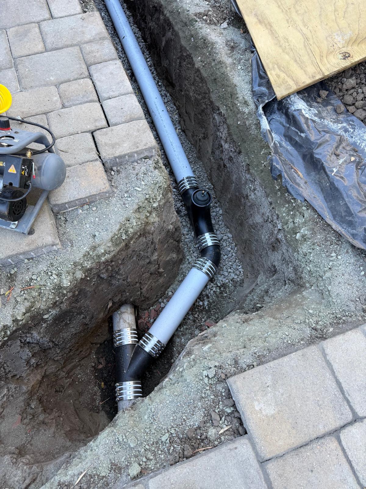 Close-up of banded no-hub couplings and cleanout on a new sewer lateral