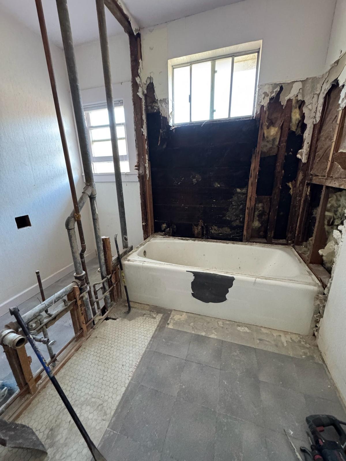 Old bathroom with tub removed and galvanized plumbing exposed