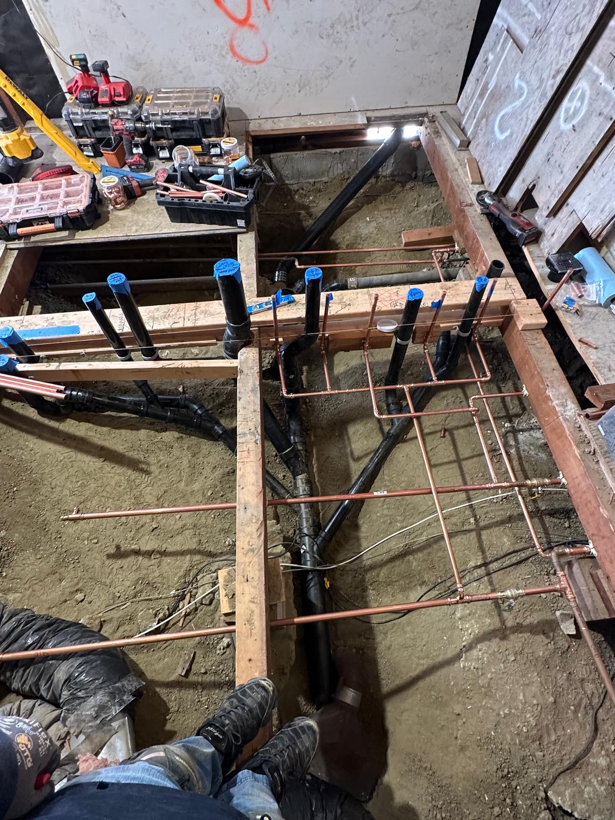 Copper water lines and DWV piping installed under the floor framing