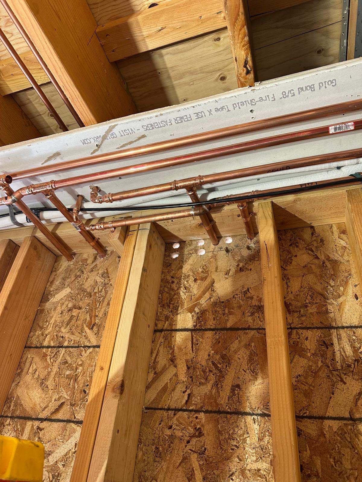 Copper water distribution lines run through ceiling framing
